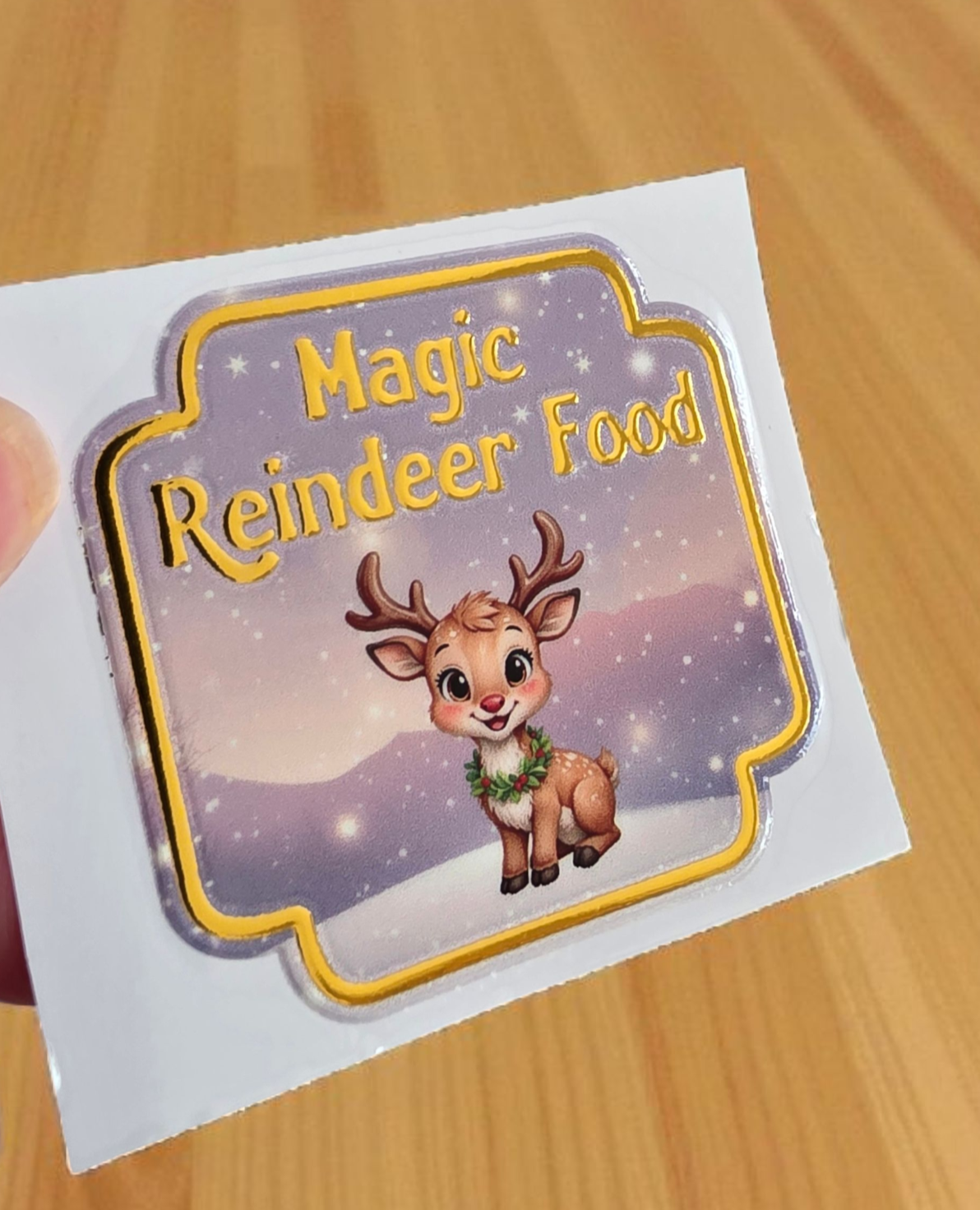 Sticker with a reindeer and 'Magic Reindeer Food' text on a wooden surface
