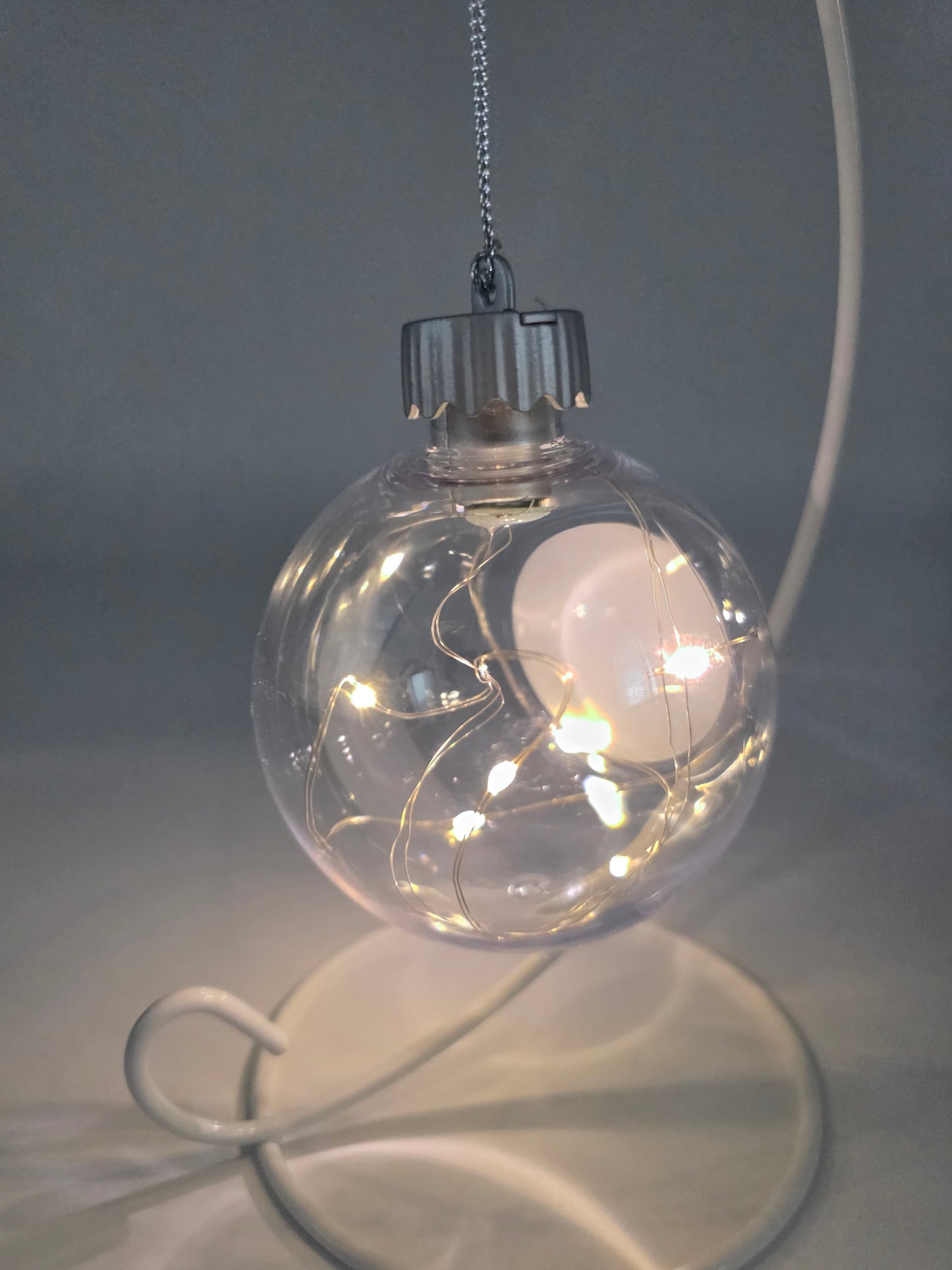 Clear glass ornament with LED lights on a gray background