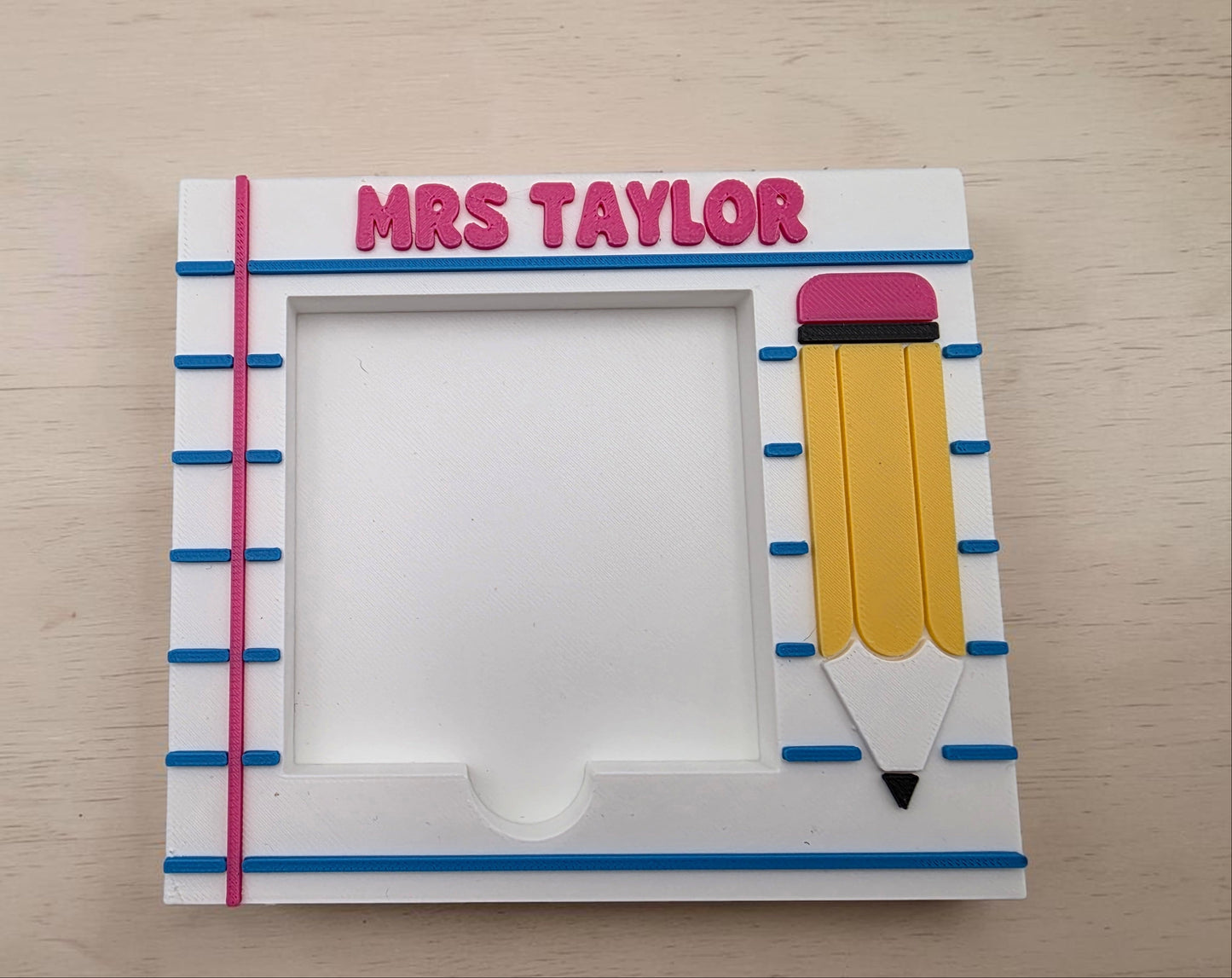 Personalized photo frame with teacher name and a pencil design on a wooden surface.